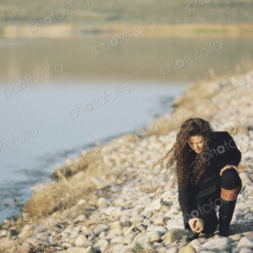 A woman collecting pebbles on the shore of a lake. A woman collecting pebbles on the shore of a lake.