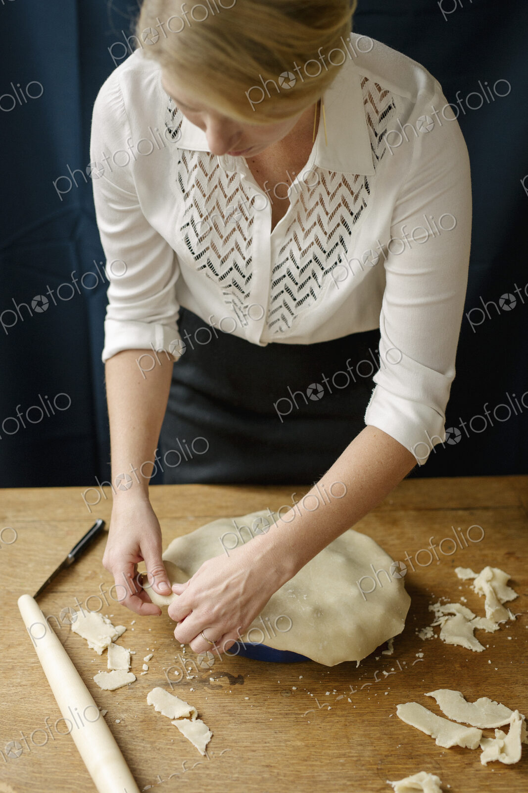 A woman crimping the pastry edge of a home made pie.