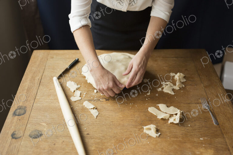 A woman crimping the pastry edge of a home made pie.