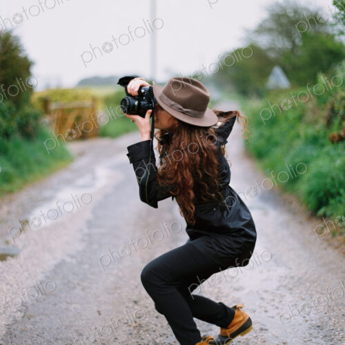 A woman crouching to take a photograph on a country road. A woman crouching to take a photograph on a country road.