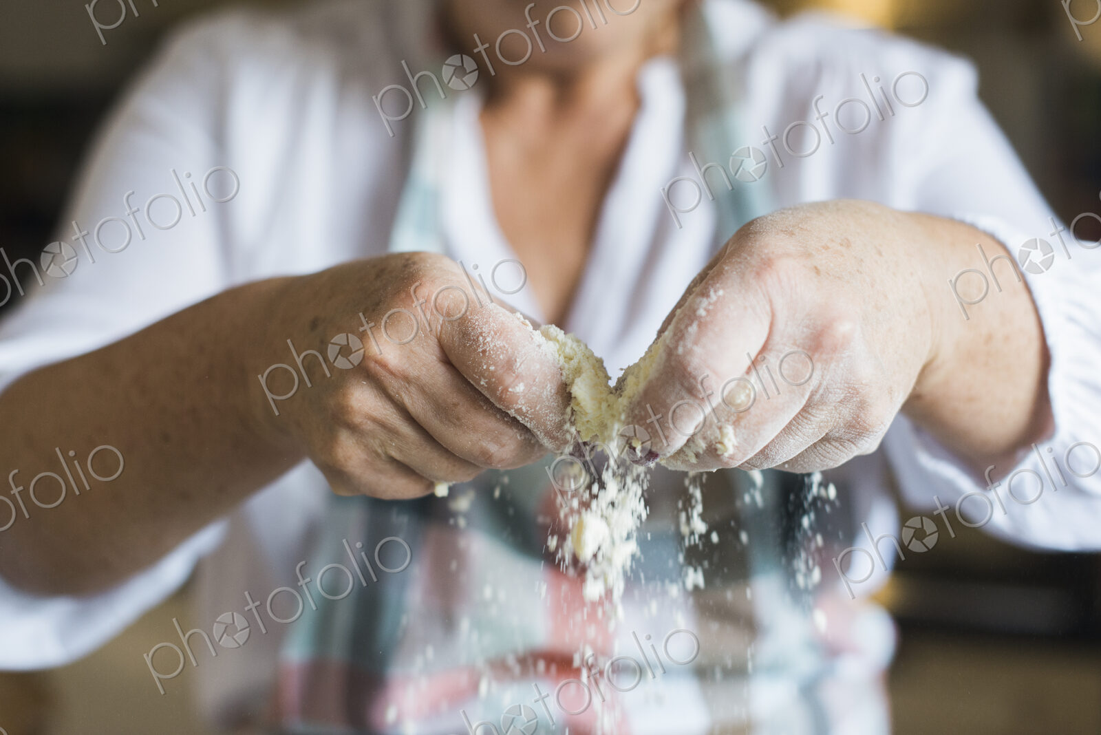 A woman crumbling and sifting white flour and butter, making a crumble topping. Home…