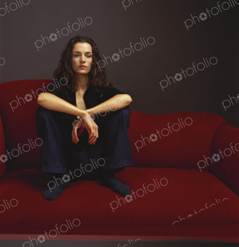 A woman dressed in black seated on a red couch.