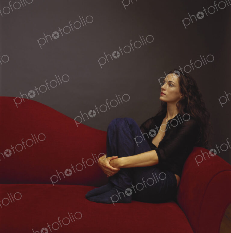 A woman dressed in black seated on a red couch.