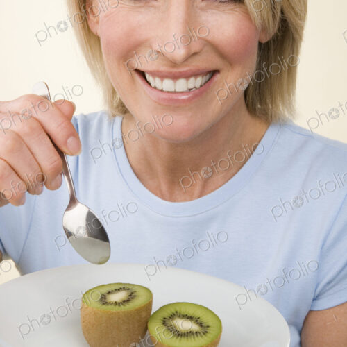 A woman eating a kiwi fruit. A woman eating a kiwi fruit.