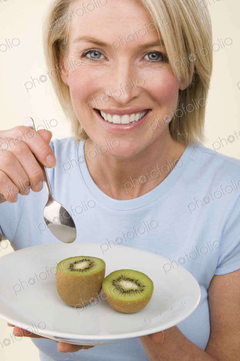 A woman eating a kiwi fruit.