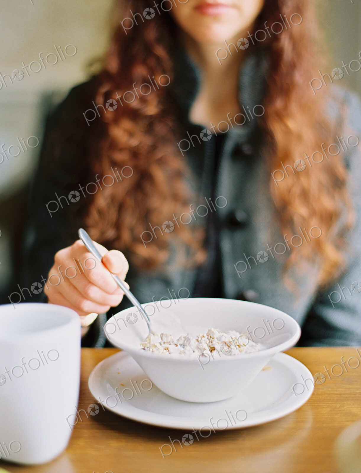 A woman eating breakfast cereal from a white bowl.