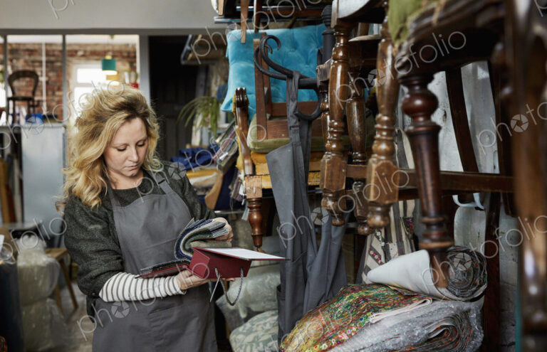 A woman flicking through a fabric sample book, looking at colours and patterns.