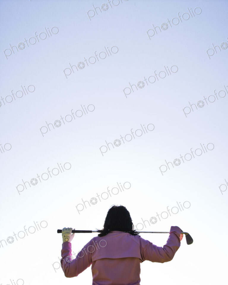 A woman golfer holding a club over her shoulders.