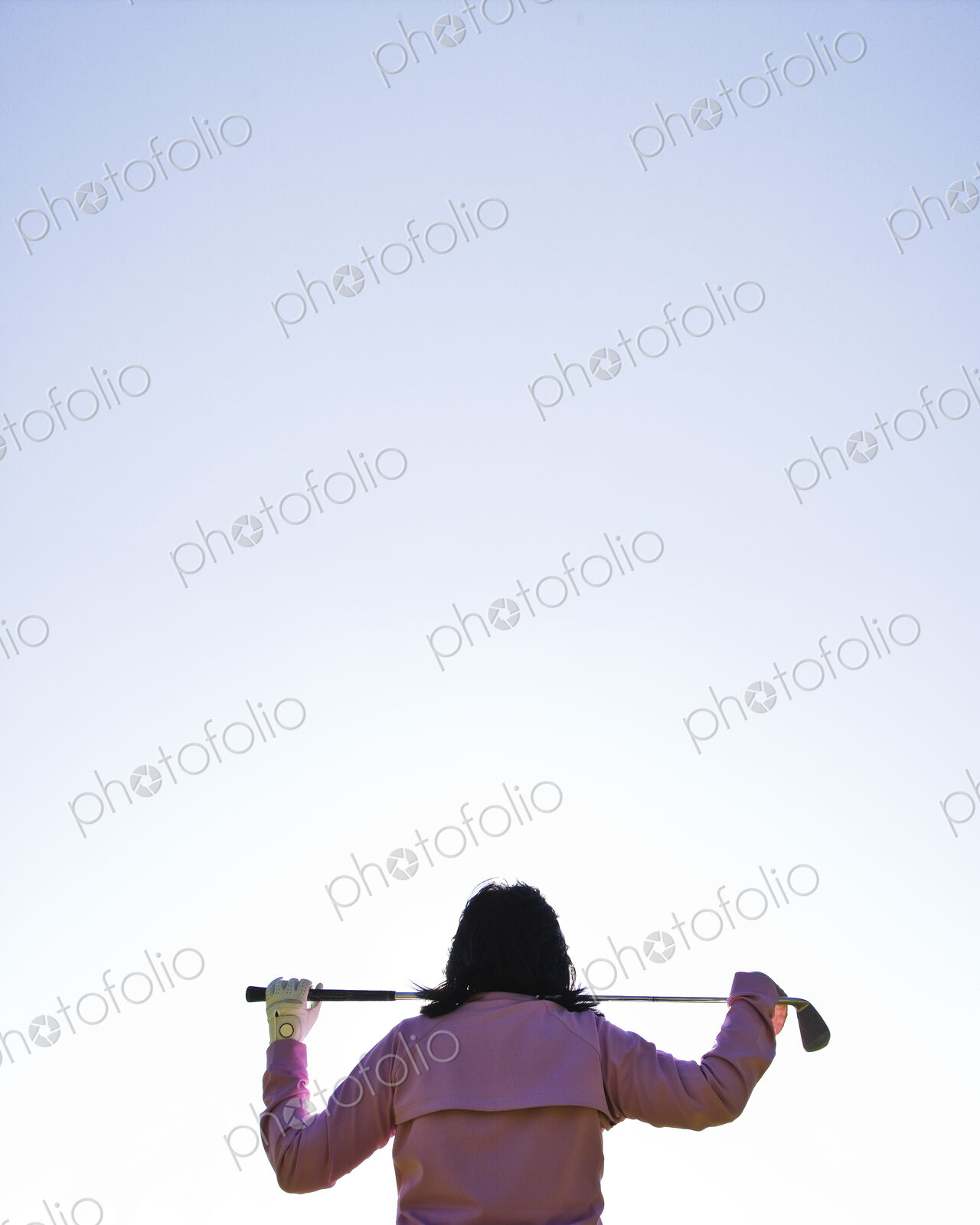 A woman golfer holding a club over her shoulders.