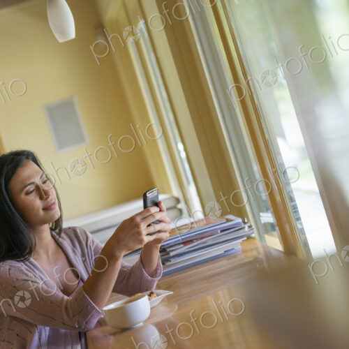 A woman having a cup of coffee and using a smart phone. A woman having a cup of coffee and using a smart phone.