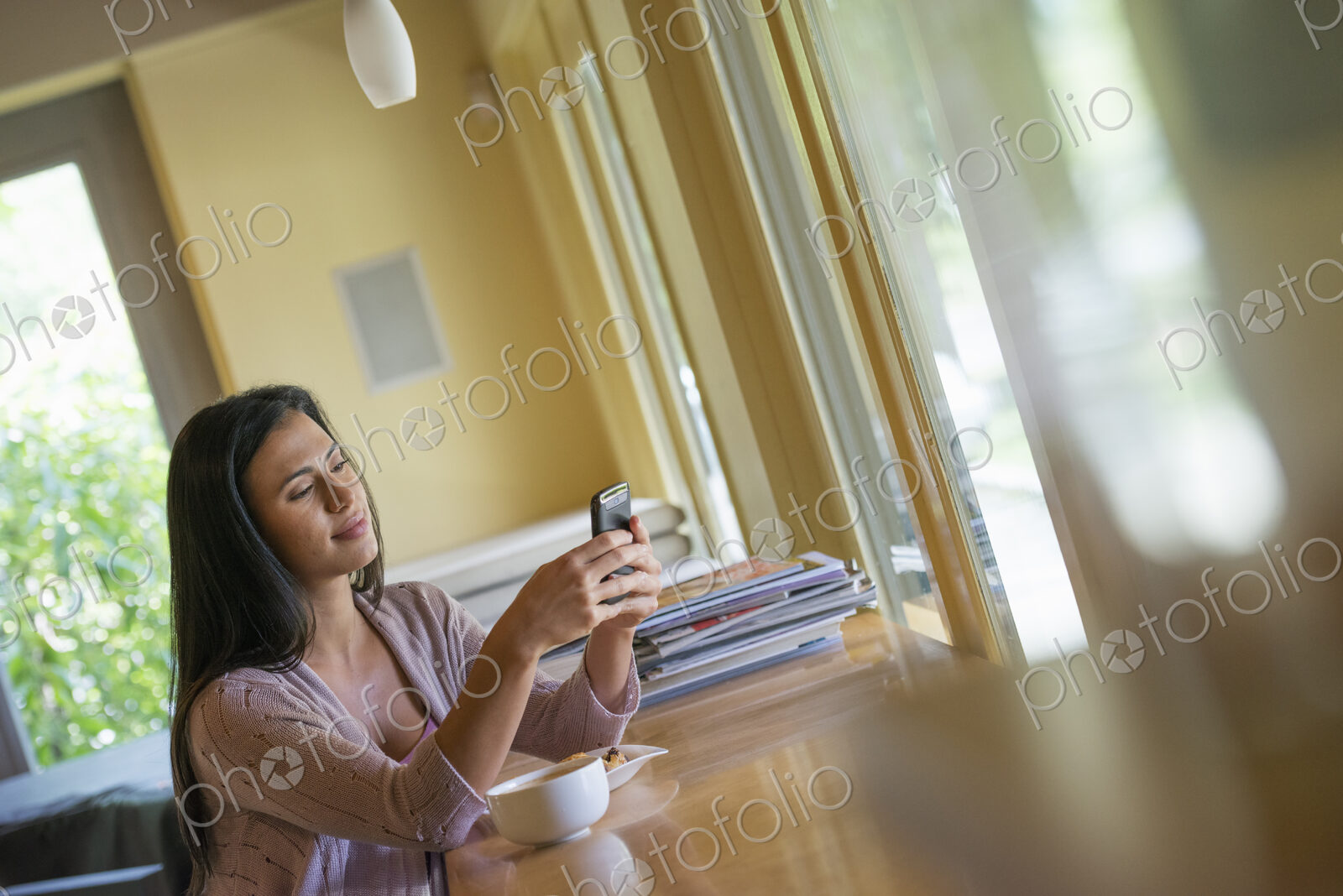 A woman having a cup of coffee and using a smart phone.