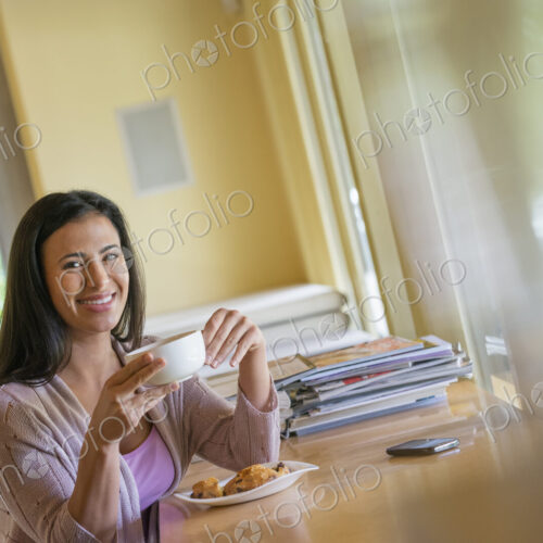 A woman having a cup of coffee. A smart phone lying on the table. A woman having a cup of coffee. A smart phone lying on the table.
