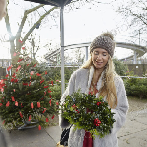 A woman holding a Christmas decorated wreath at a garden centre. A woman holding a Christmas decorated wreath at a garden centre.