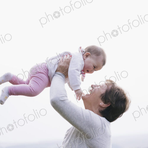 A woman holding a baby girl in the air above her head. A woman holding a baby girl in the air above her head.