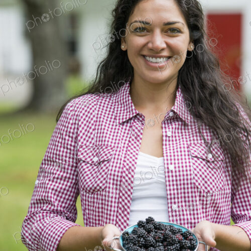 A woman holding a bowl of freshly picked blackberries.