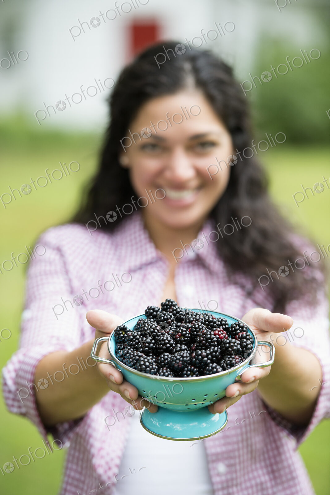A woman holding a bowl of freshly picked blackberries.