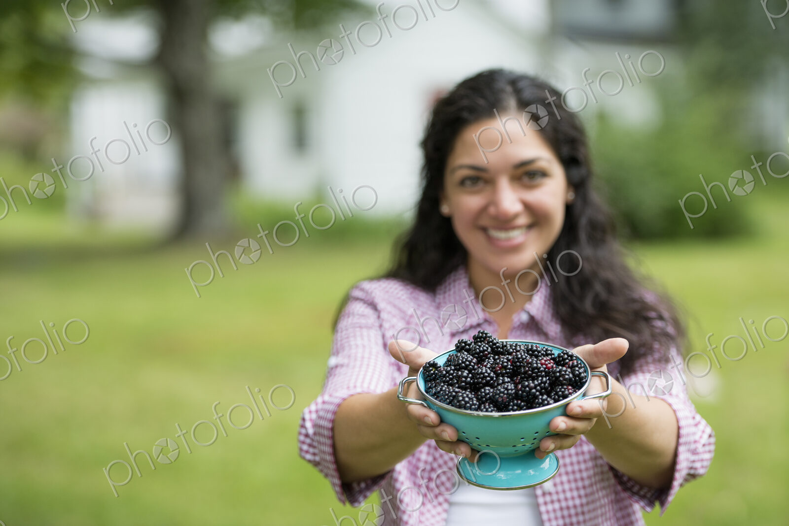A woman holding a bowl of freshly picked blackberries.