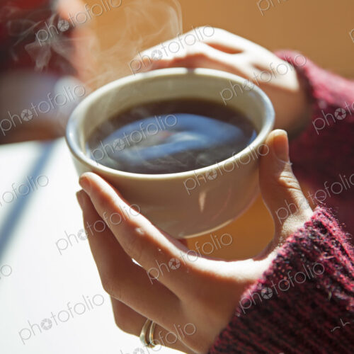 A woman holding a cup of hot coffee in her hands. A woman holding a cup of hot coffee in her hands.