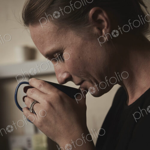 A woman holding a fresh brewed cup of coffee to her nose.
