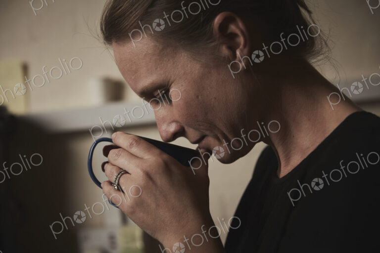 A woman holding a fresh brewed cup of coffee to her nose.