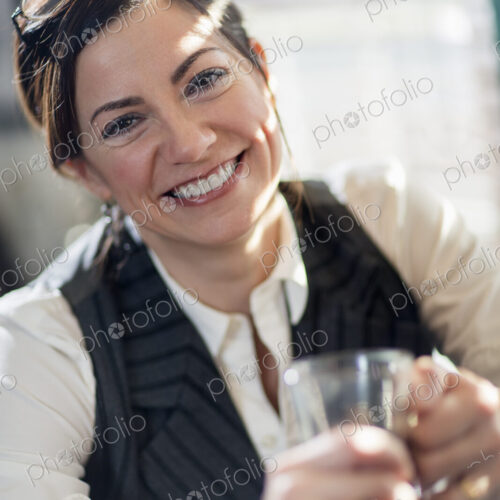 A woman holding a glass and smiling at the camera. A working lunch. A woman holding a glass and smiling at the camera. A working lunch.