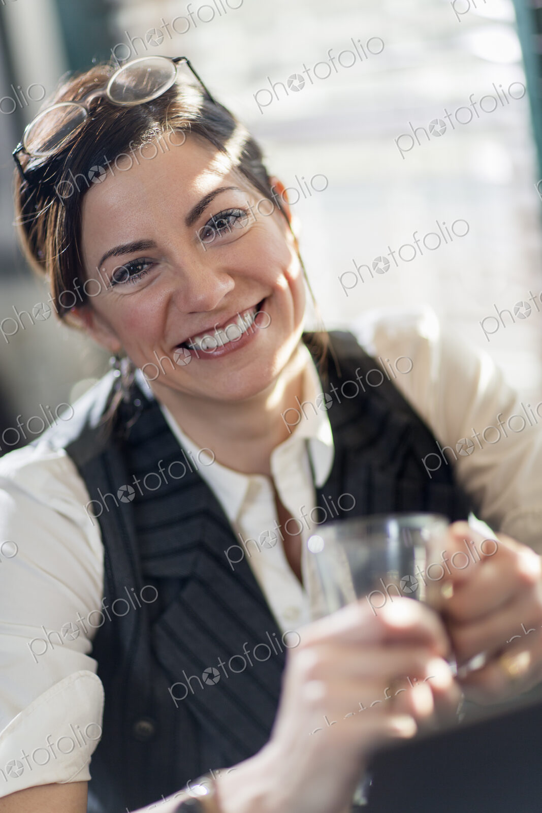 A woman holding a glass and smiling at the camera. A working lunch.