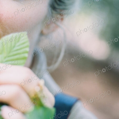 A woman holding a green ridged beech leaf.