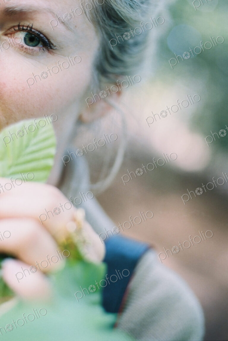 A woman holding a green ridged beech leaf.
