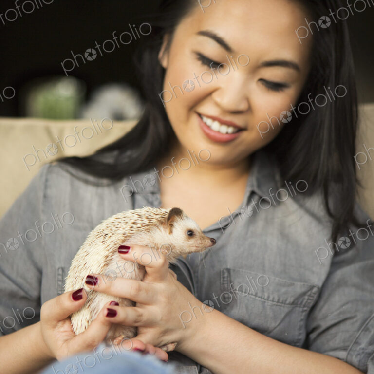 A woman holding a hedgehog in her hands.