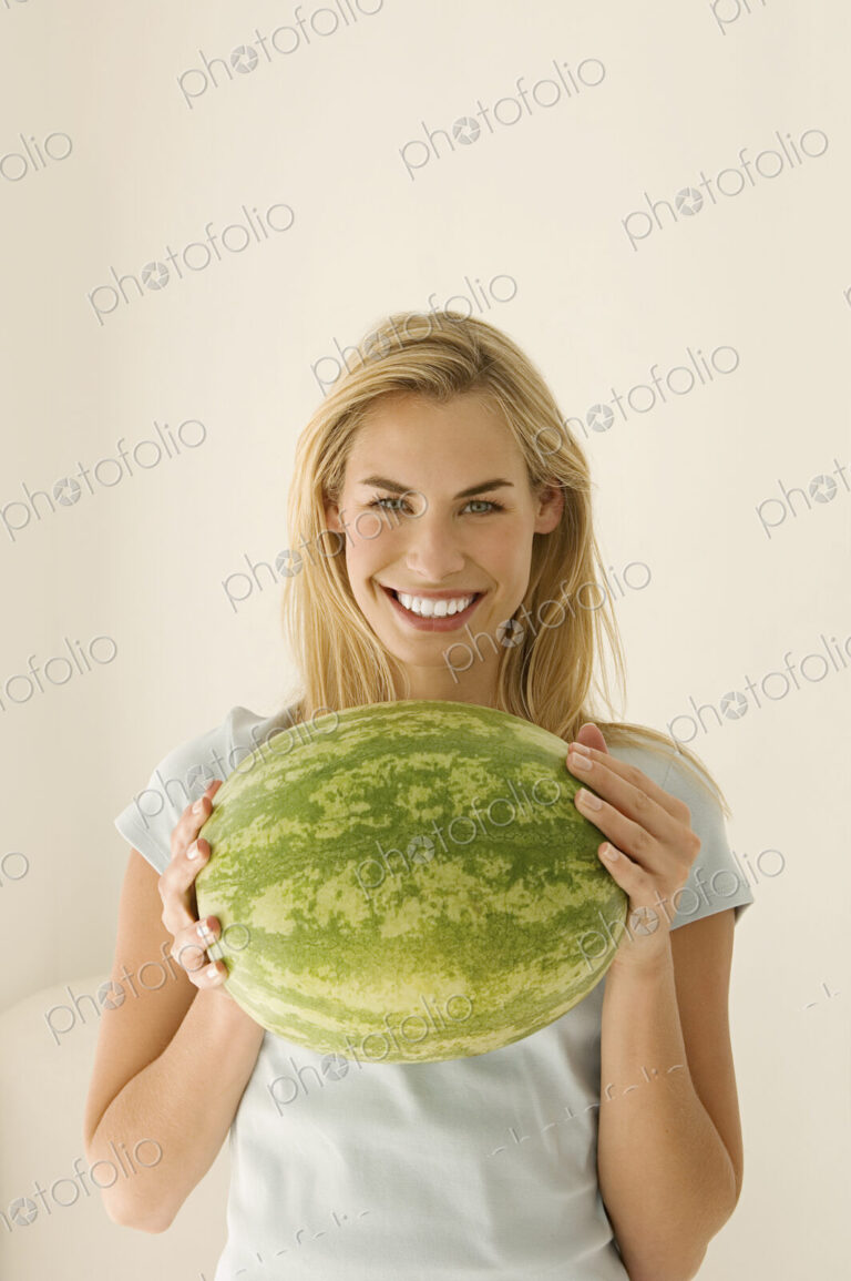 A woman holding a large green watermelon.
