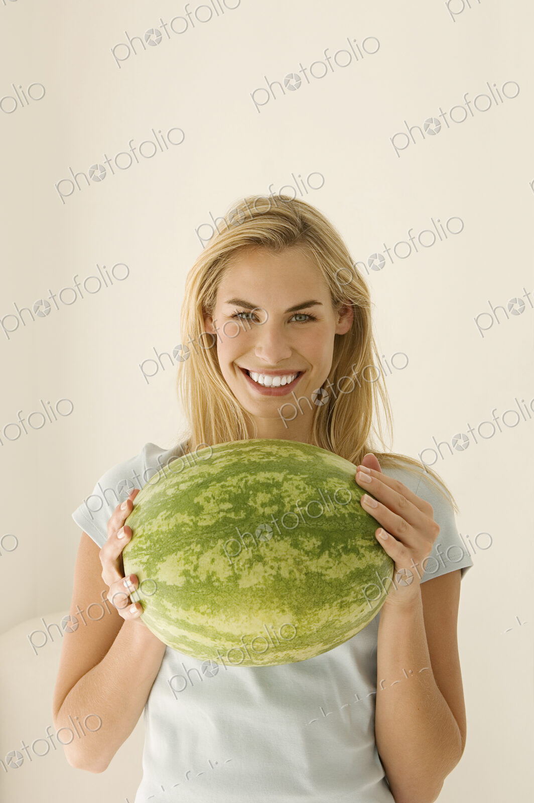 A woman holding a large green watermelon.