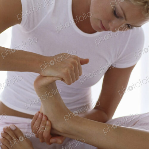 A woman holding a person's foot and massaging and flexing the toes. A woman holding a person's foot and massaging and flexing the toes.
