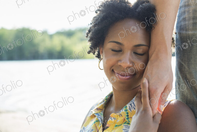 A woman holding a person's hand to her cheek and smiling.
