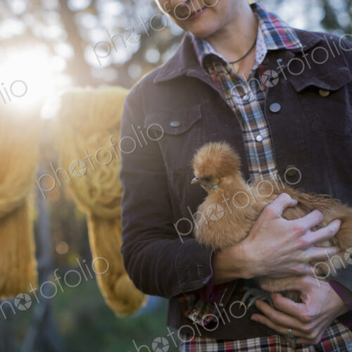 A woman holding a small brown fluffy chicken. A woman holding a small brown fluffy chicken.