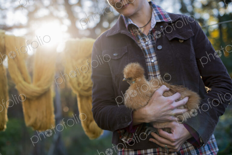 A woman holding a small brown fluffy chicken.