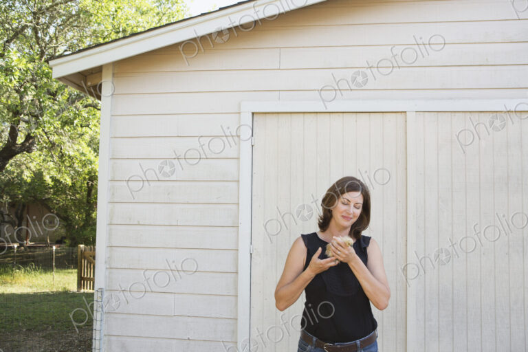 A woman holding a small fluffy chick, a baby bird in her two hands.