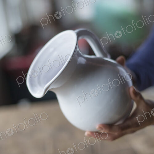 A woman holding a white pottery jug in an antique goods and furniture store. A woman holding a white pottery jug in an antique goods and furniture store.
