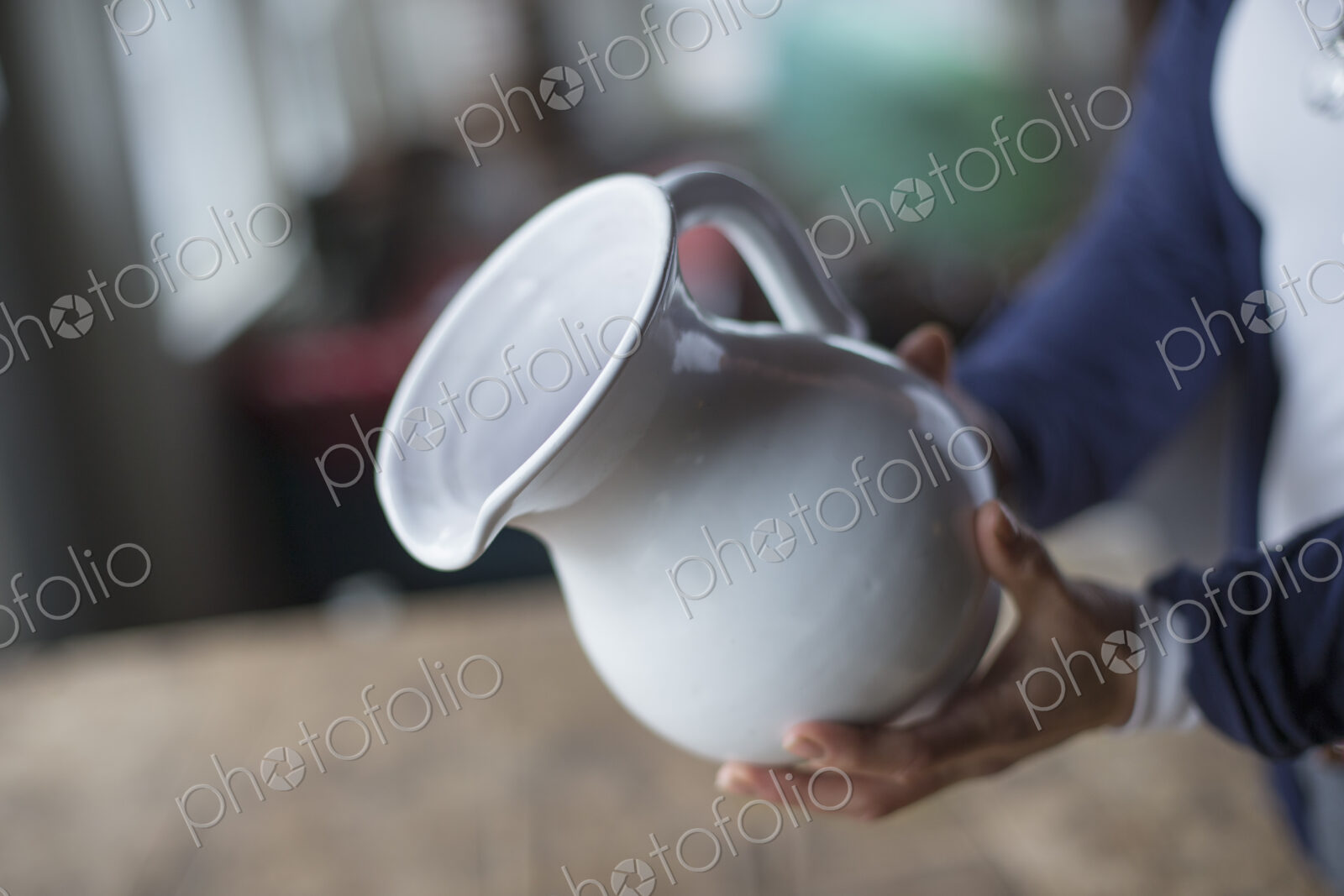 A woman holding a white pottery jug in an antique goods and furniture store.