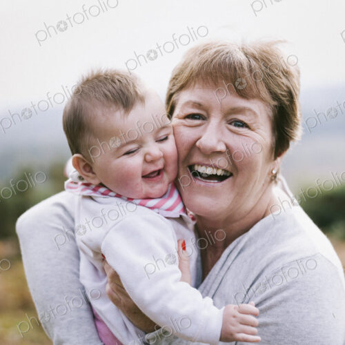 A woman holding a young baby close to her and laughing.