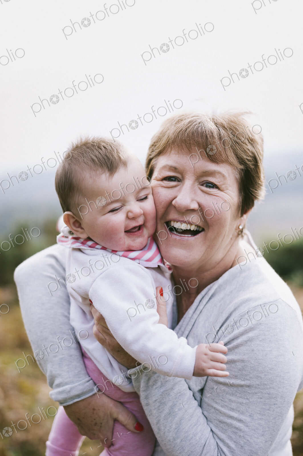 A woman holding a young baby close to her and laughing.