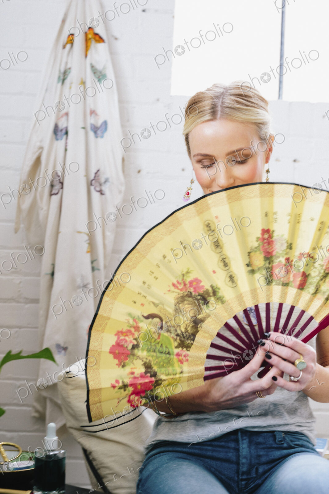 A woman holding an open Oriental fan hiding her face.