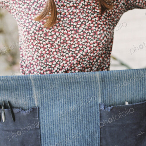 A woman holding and wrapping a denim apron aroud her waist. A woman holding and wrapping a denim apron aroud her waist.
