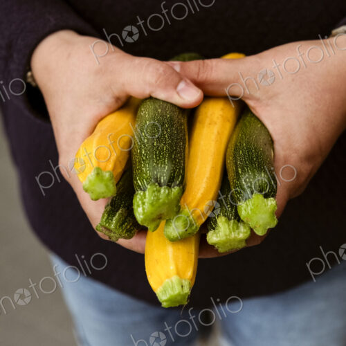 A woman holding out her hands holding a bunch of freshly picked yellow and green…