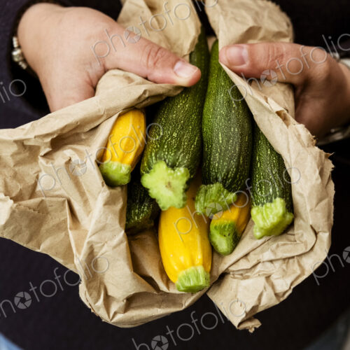 A woman holding out her hands holding a bunch of freshly picked yellow and green…