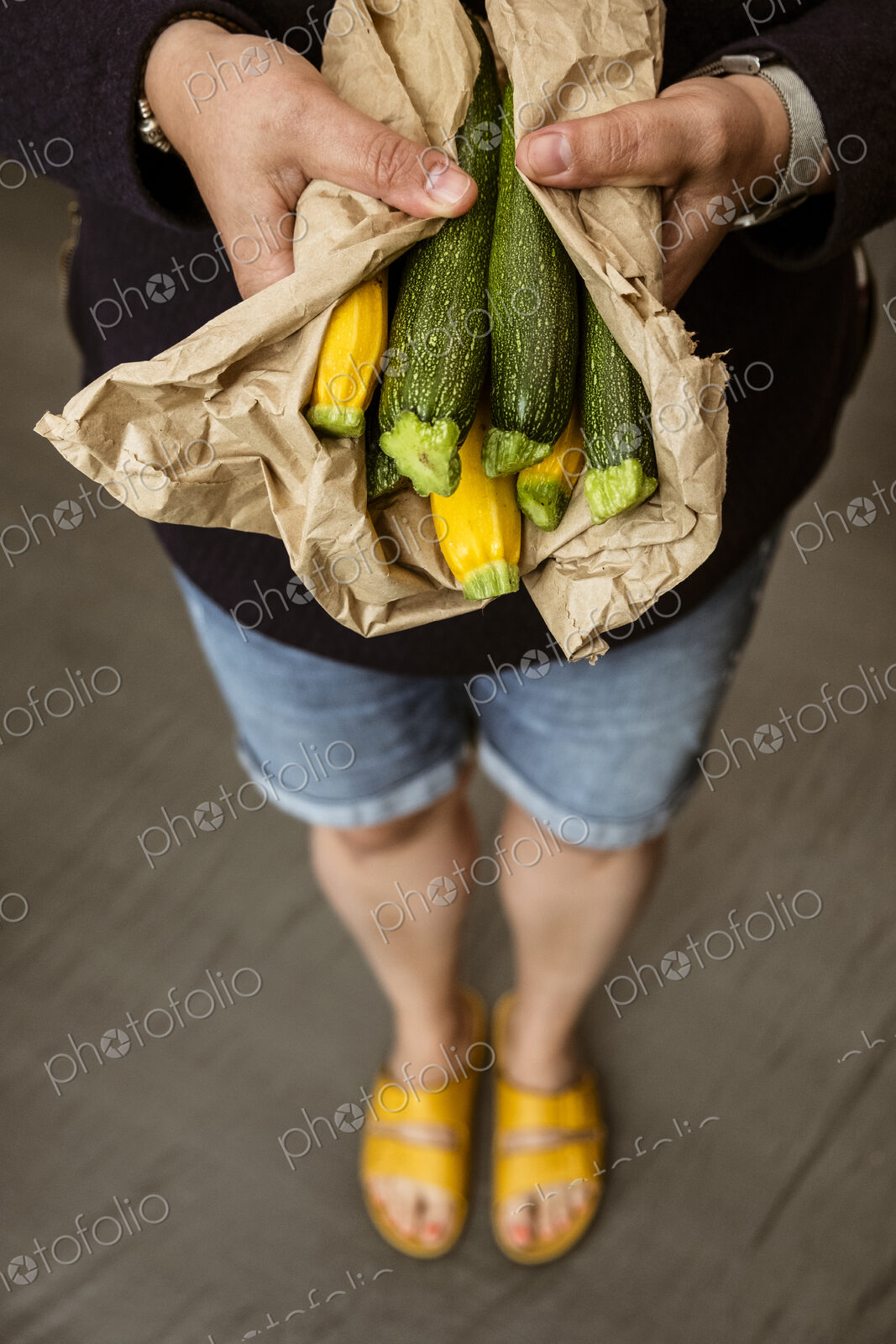 A woman holding out her hands holding a bunch of freshly picked yellow and green…