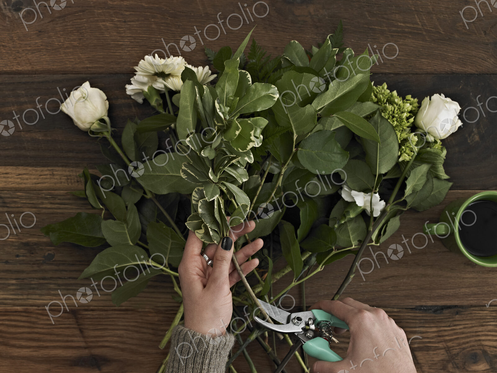 A woman holding secateurs and cutting the base of flower stems for a flower…