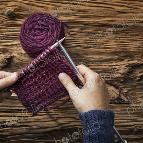 A woman holding two knitting needles, and a piece of knitting, in purple wool. A woman holding two knitting needles, and a piece of knitting, in purple wool.