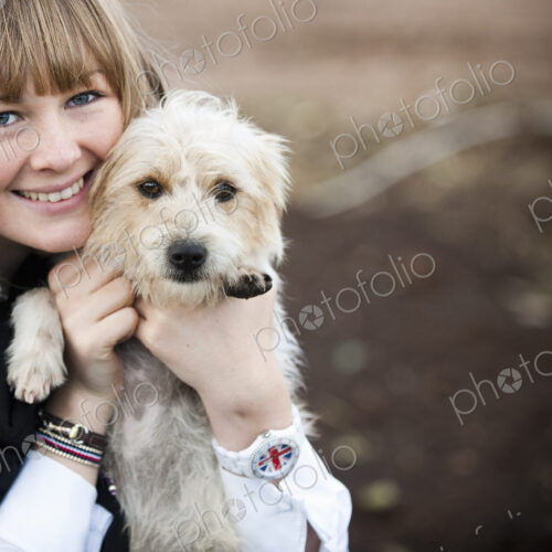 A woman hugging a small hairy terrier puppy. A woman hugging a small hairy terrier puppy.