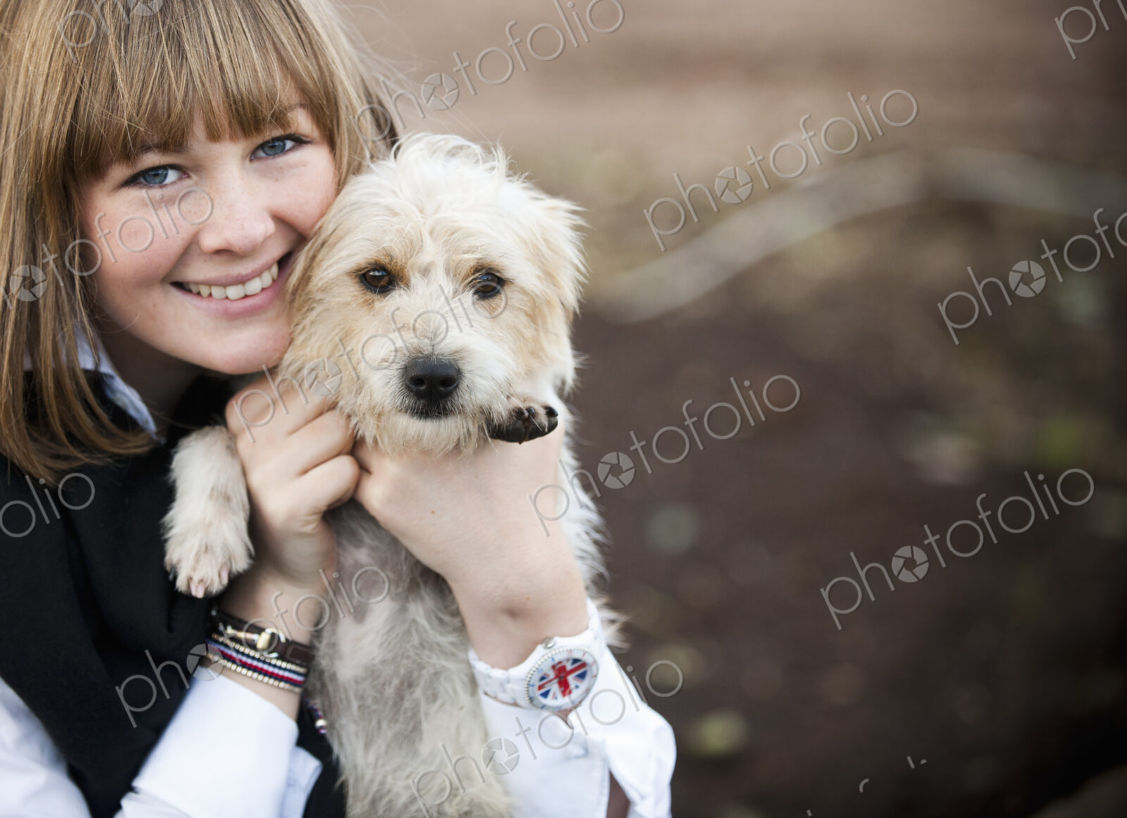 A woman hugging a small hairy terrier puppy.