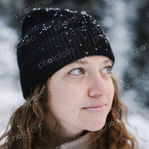 A woman in a black hat dusted with snow outdoors.